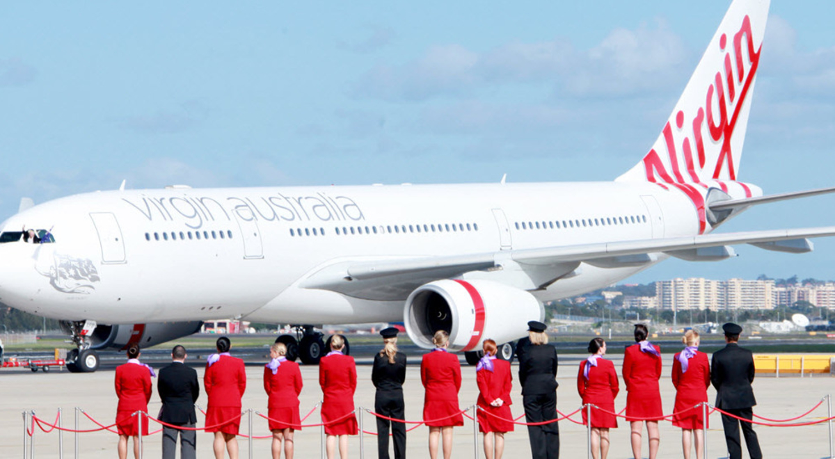 Crew members standing on a red carpet looking at one of Virgin Australia's planes