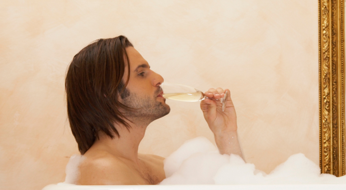 Couple dipped in a bathtub drinking champagne