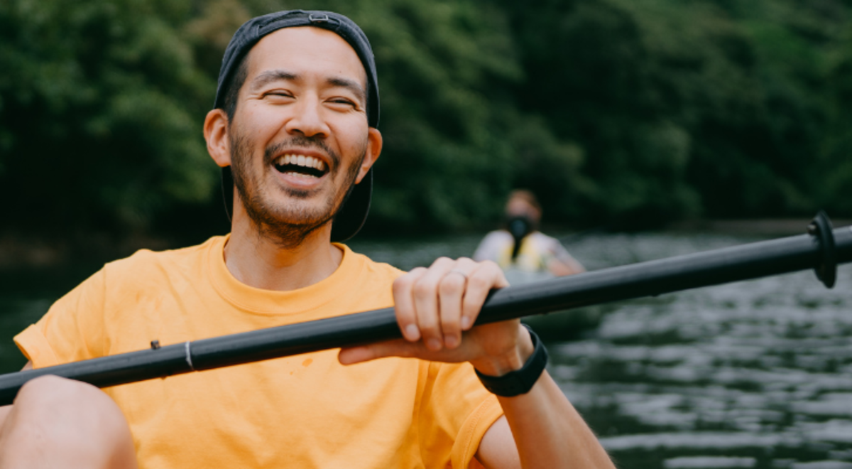 A guy smiling while canoeing in the river