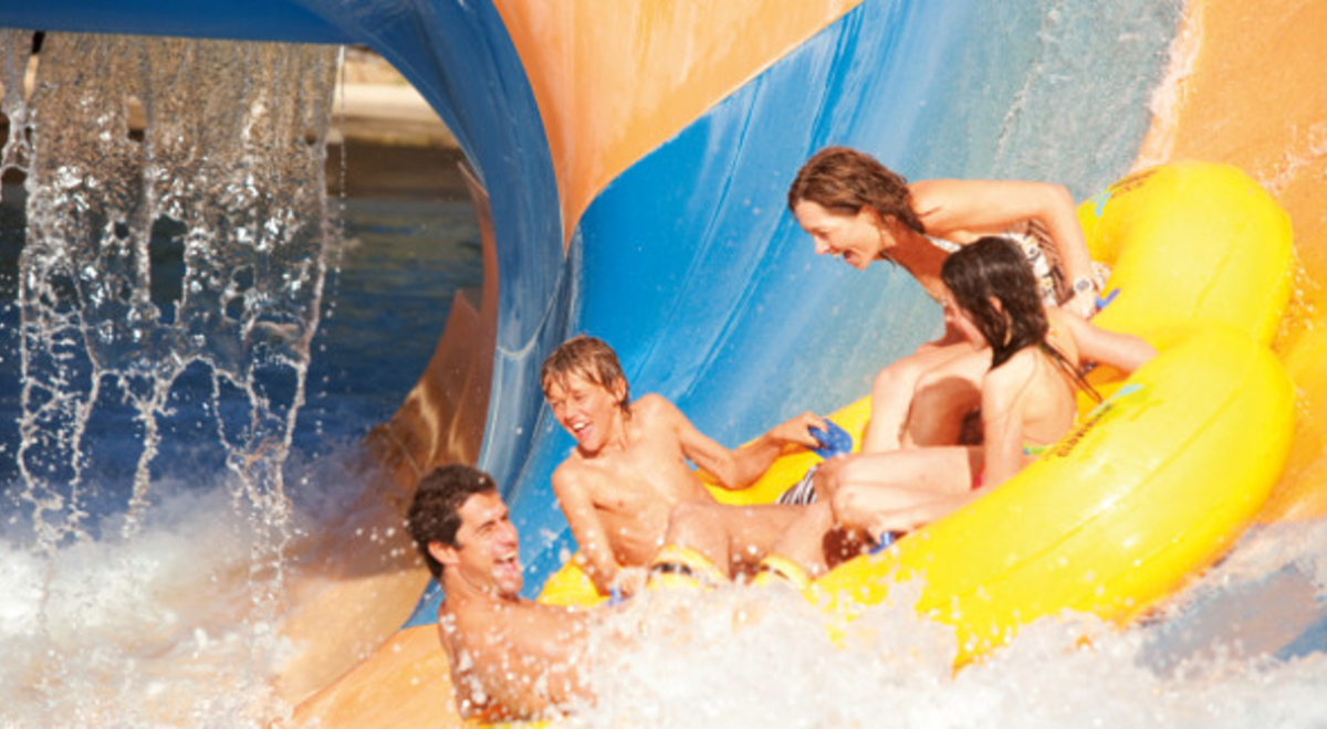 Family of four riding an inflatable in a waterpark slide