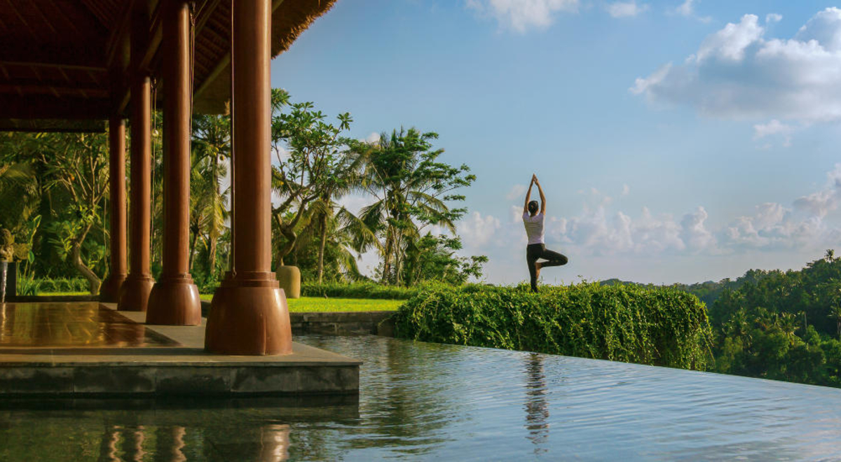 A woman performs yoga by a pool at Mandapa Ritz Carlton Ubud in Bali.