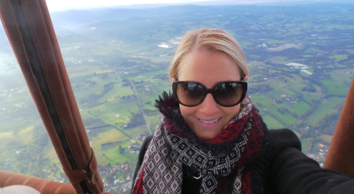 Woman in an air balloon wearing sunglasses and a red and black scarf 