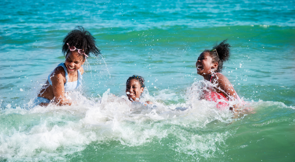 Three kids splashing in the waves at a Florida beach