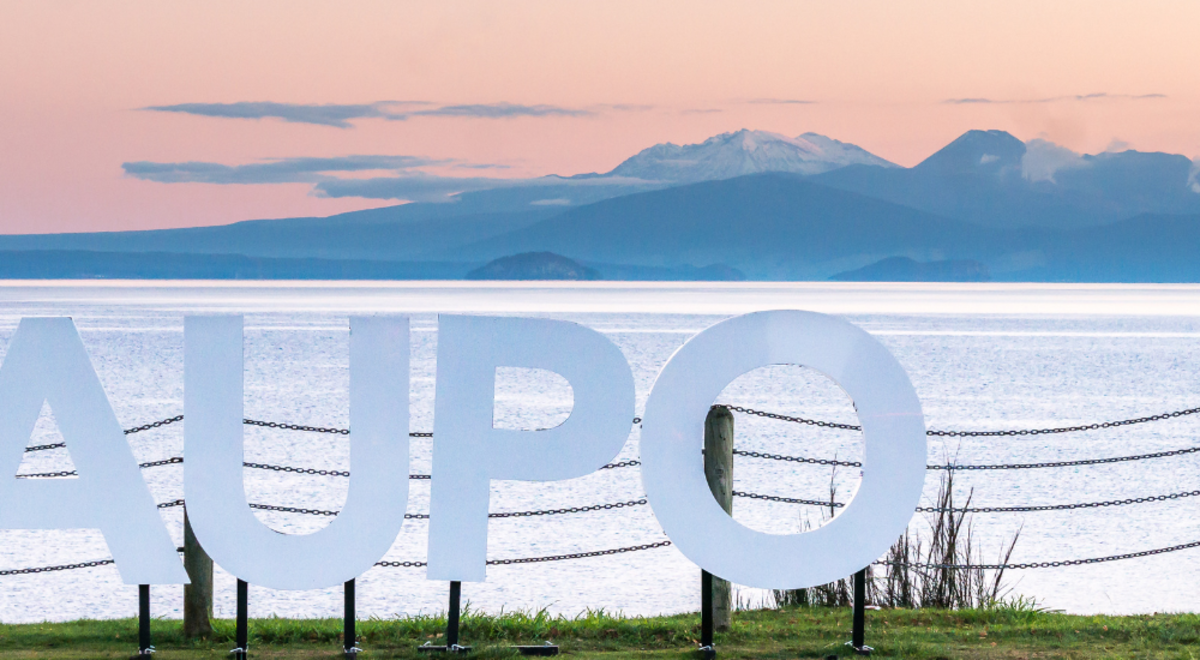 Taupo sign infront of Lake Taupo at sunset