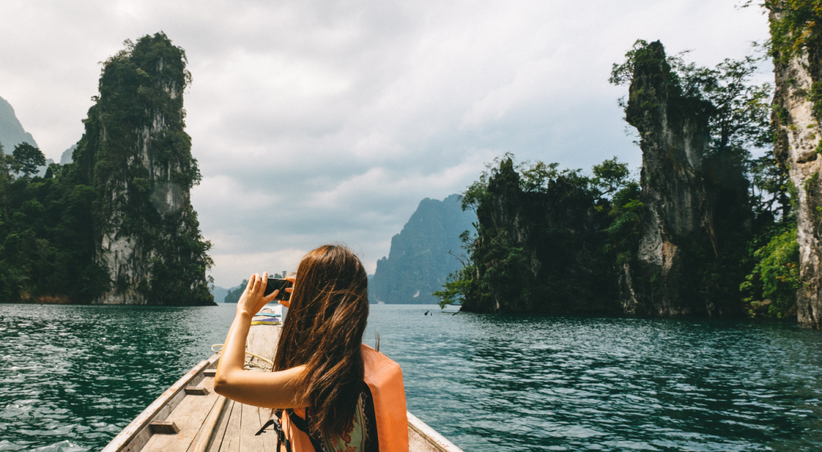 Female tourist exploring lush Jungle lake surrounded by limestone cliffs in Khao Sok National Park