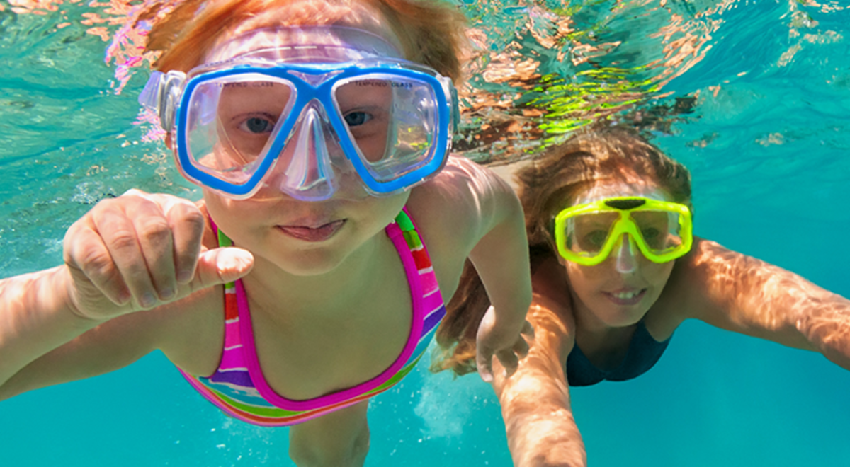 Two kids wearing snorkelling gear in the water