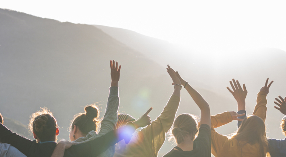 Group of nine admiring the view with their hands in the air 