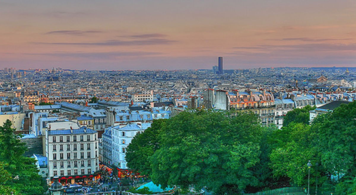 The city at dusk with green trees at the forefront 