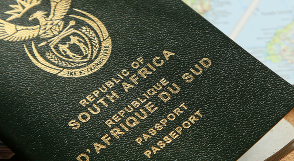 A South African passport rests on an open atlas