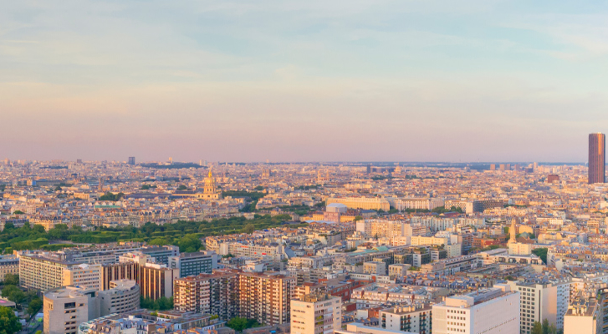 A panoramic aerial view of Paris at sunset with the Eiffel Tower in the center