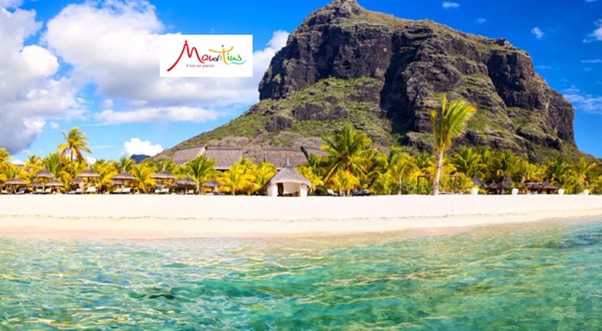 A view from a lagoon in Mauritius of the beach, palms and a mount of tall bluffs