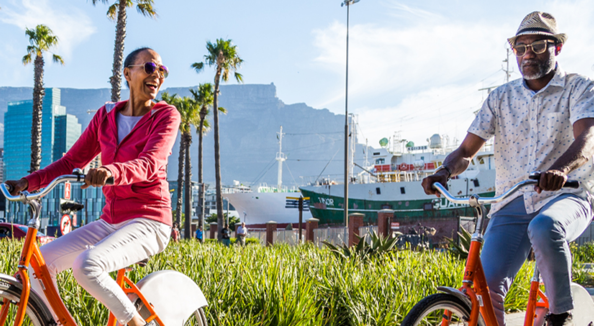 A couple riding orange bikes past a wharf