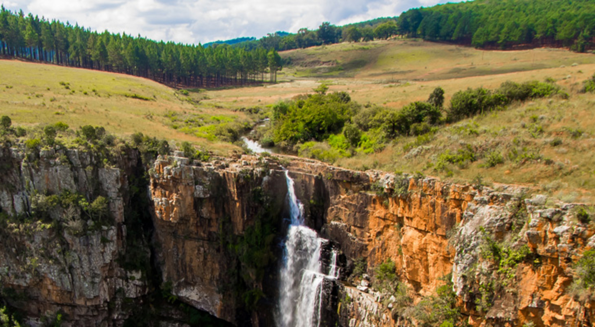 A panoramic view of a long cliff face with a waterfall cascading down the middle.