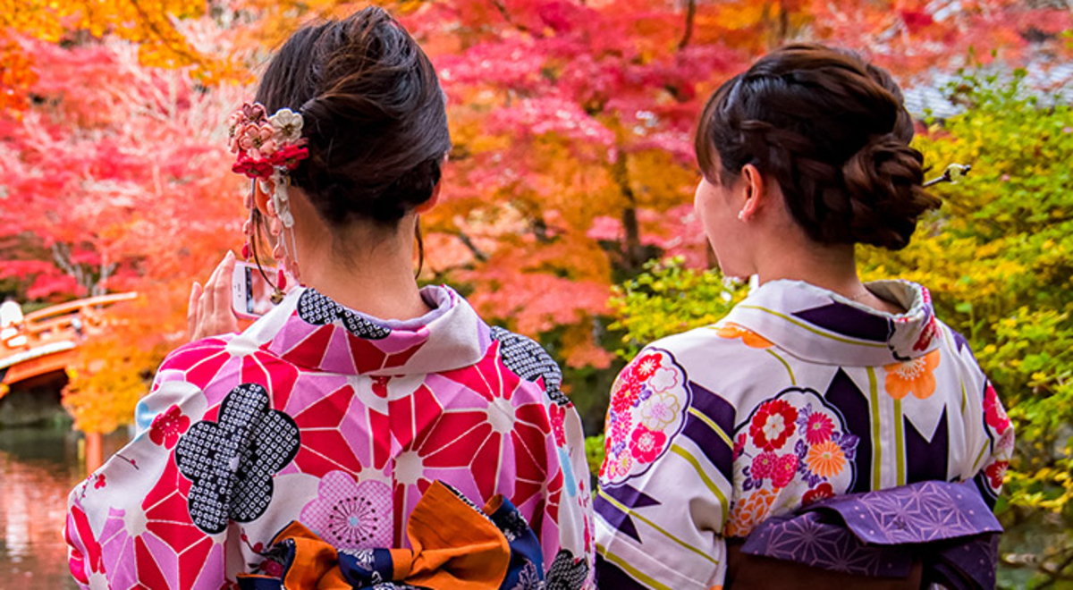 Two people wearing traditional Japanese clothing in a beautiful and colourful Japanese garden