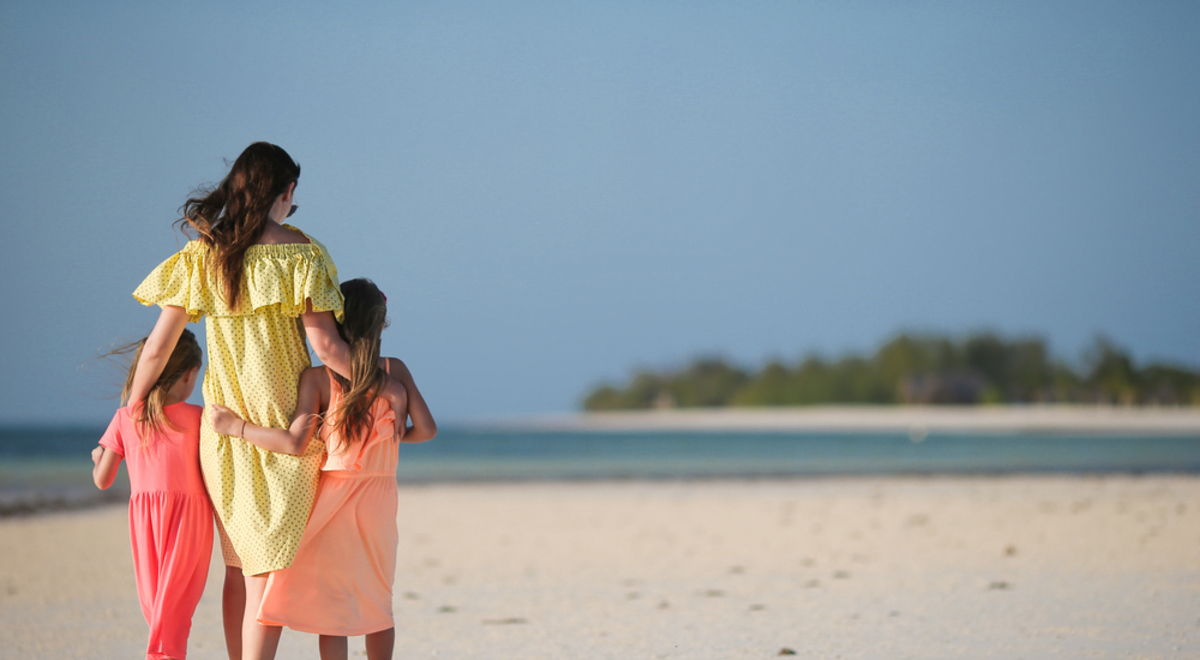 Woman walking along a beach with two young girls