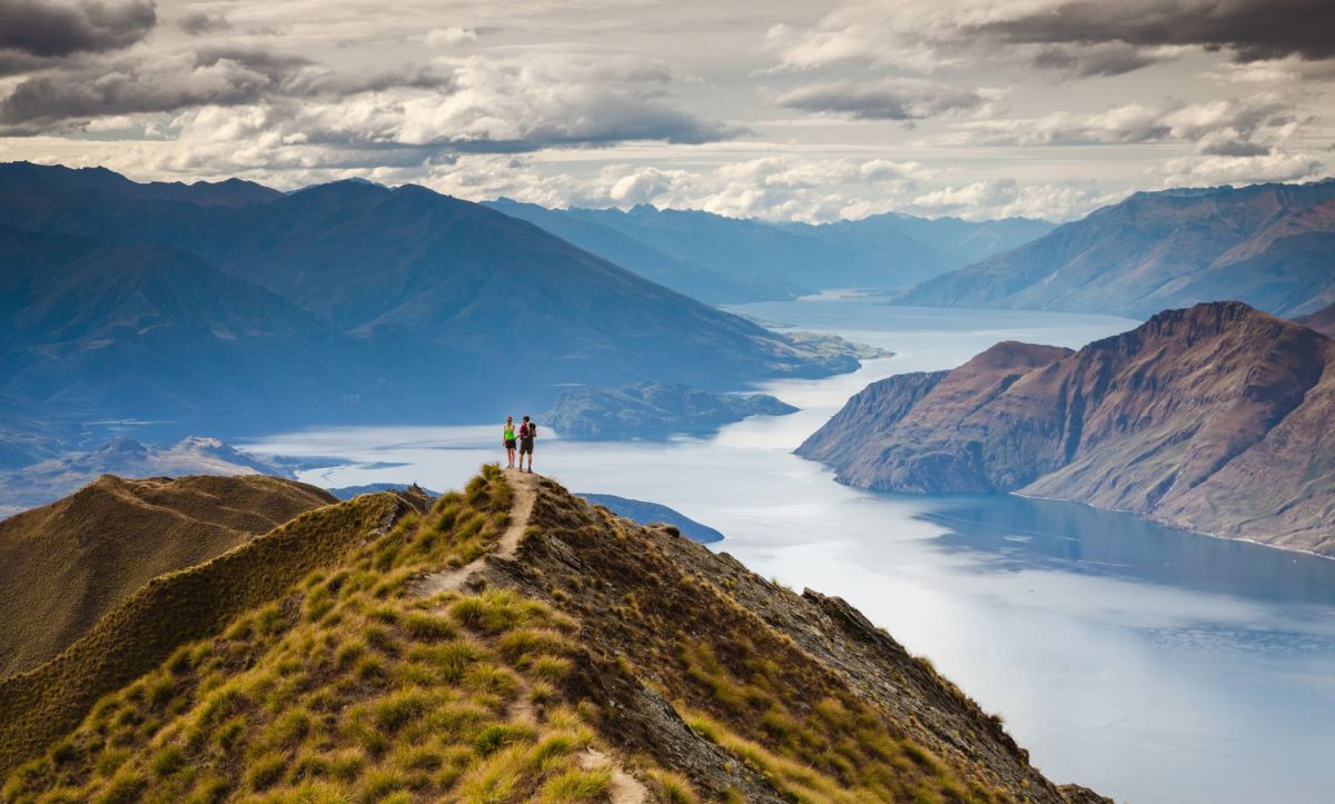 Couple standing on a grassy hill overlooking mountains and rivers