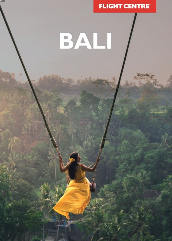 A woman rides a large swing over a rainforest