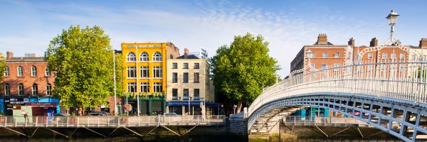 White arch bridge over a smooth reflective river with multi-storey buildings along the side