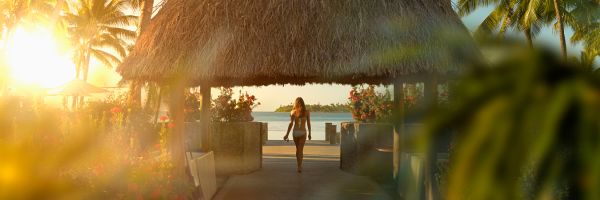 Woman in a white bikini under a thatched gazebo