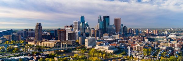 Minneapolis city - skyscrapers, bridges over a river, dense trees and a clear sky