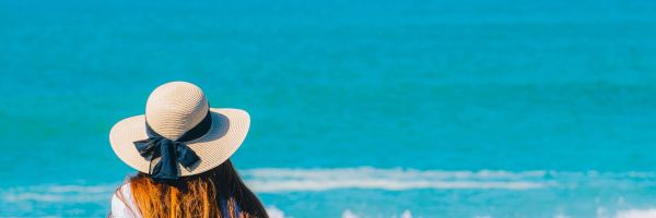 Lady sitting on tree branches on beach looking out at water