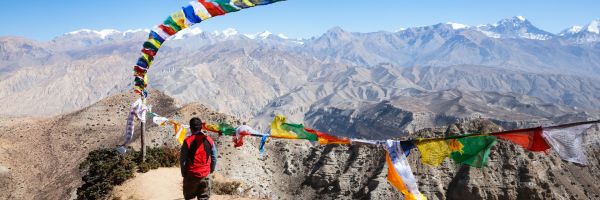Man standing on a mountain standing beneath a string of flags