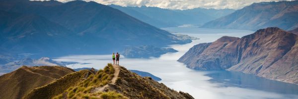 Couple standing on a grassy hill overlooking mountains and rivers