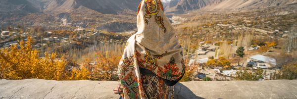 Woman wearing a colourful Burka looking out over Pakistan