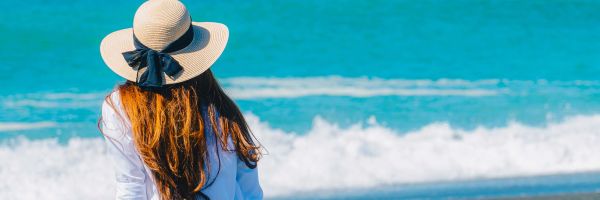 Lady sitting on tree branches on beach looking out at water