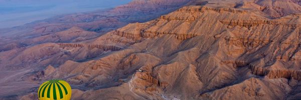 Hot air balloon over canyon with lake in background