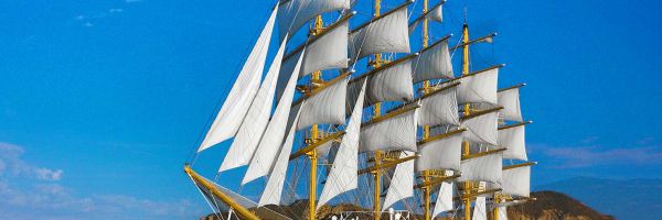 Modern sailboat passing sheer cliffs