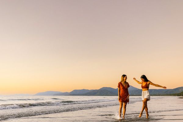 Two women happily walking and splashing through the surf in the early afternoon
