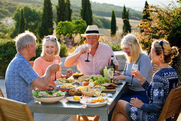 Elderly friends drinking wine around a table outside