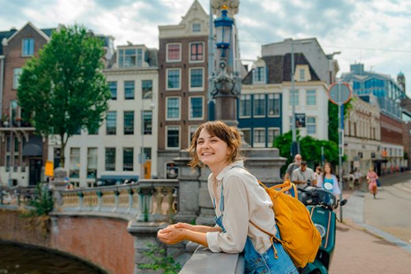lady smiling and leaning over edge of bridge in amsterdam