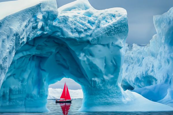 Sail boat behind iceberg