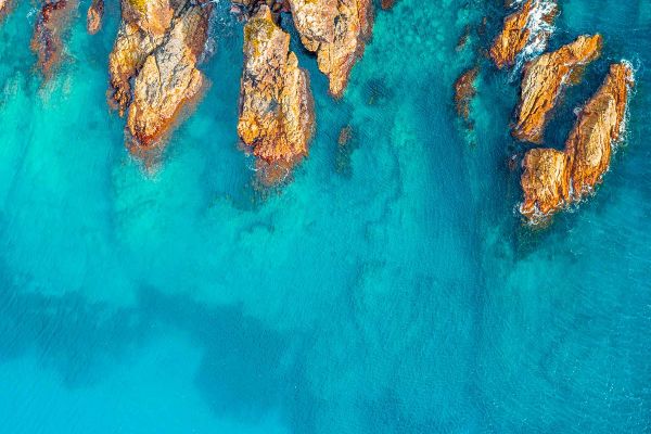 Aerial shot of clear water up against rock face