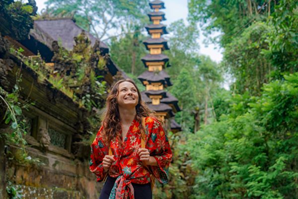 girl with backpack smiling while walking through temple in bali