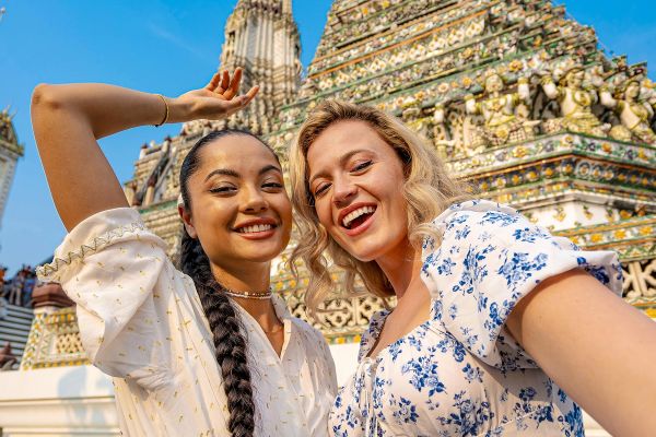 Two women posing in front of a temple in Thailand