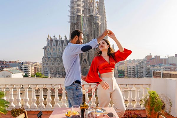 couple dancing on balcony overlooking large building in barcelona