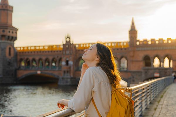 girl leaning over railing of bridge over river in berlin