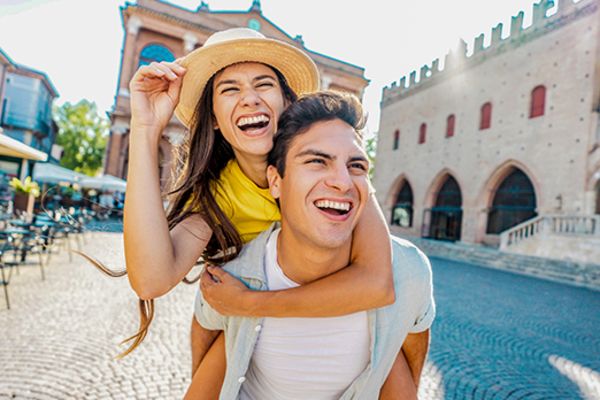 Man giving a woman a piggyback through a European city