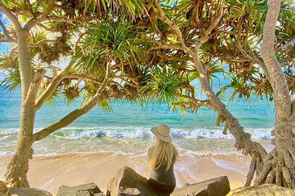 Woman sitting under trees on a beach