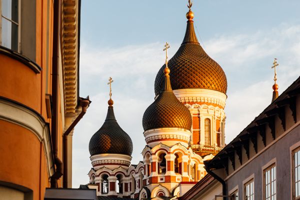 Ornate Russian Orthodox church domes glowing in warm sunlight between historic buildings in a European old town