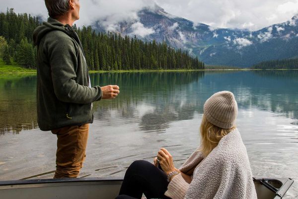 Couple overlooking lake with snowcapped mountains in the background. Lady sitting in a kayak