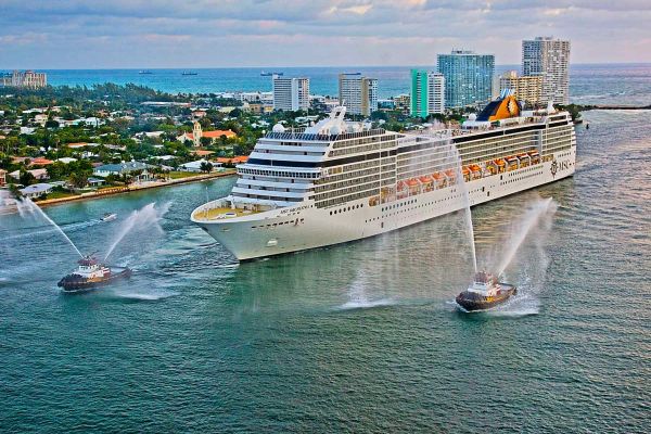 Drone shot of MSC cruise ship cruising past city with a smaller boat on either side