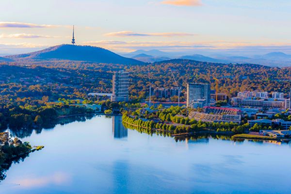 Reflective lake and rolling green hills surrounding city buildings