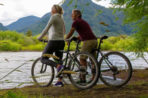 Cyclist couple pause, look across river to hills