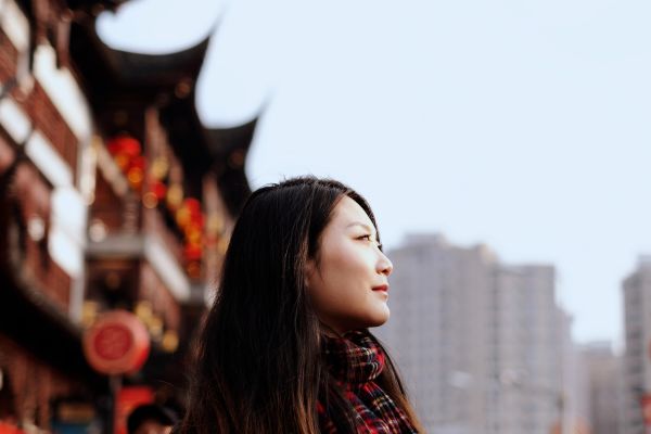 Closeup of a woman in China, with tall pagodas in the background