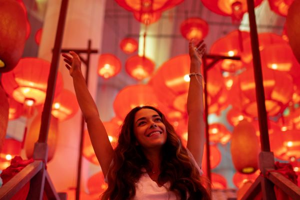 Woman cheering underneath dozens of red Chinese lanterns 