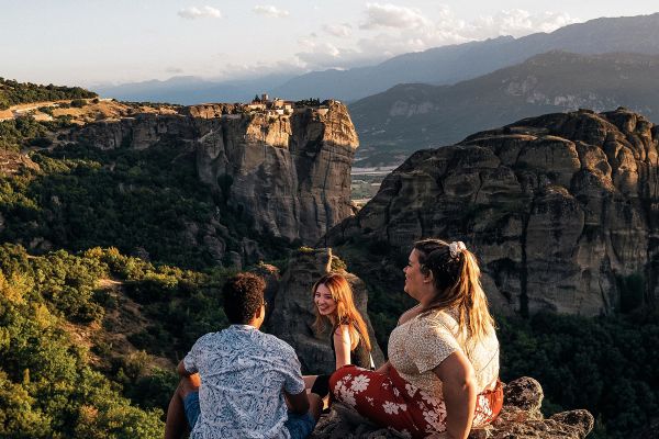 Three friends sitting on a rock looking out at craggy hills